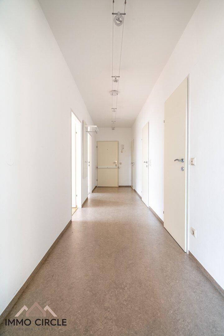 Langer, heller Flur mit Linoleumboden und mehreren Türen zu den Zimmern.