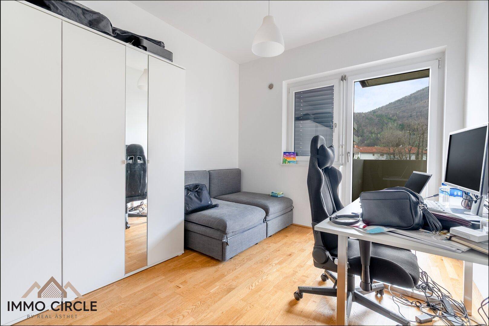 Helles Zimmer mit Parkettboden, Schreibtisch und Schlafsofa, ideal als Gäste- oder Arbeitszimmer.