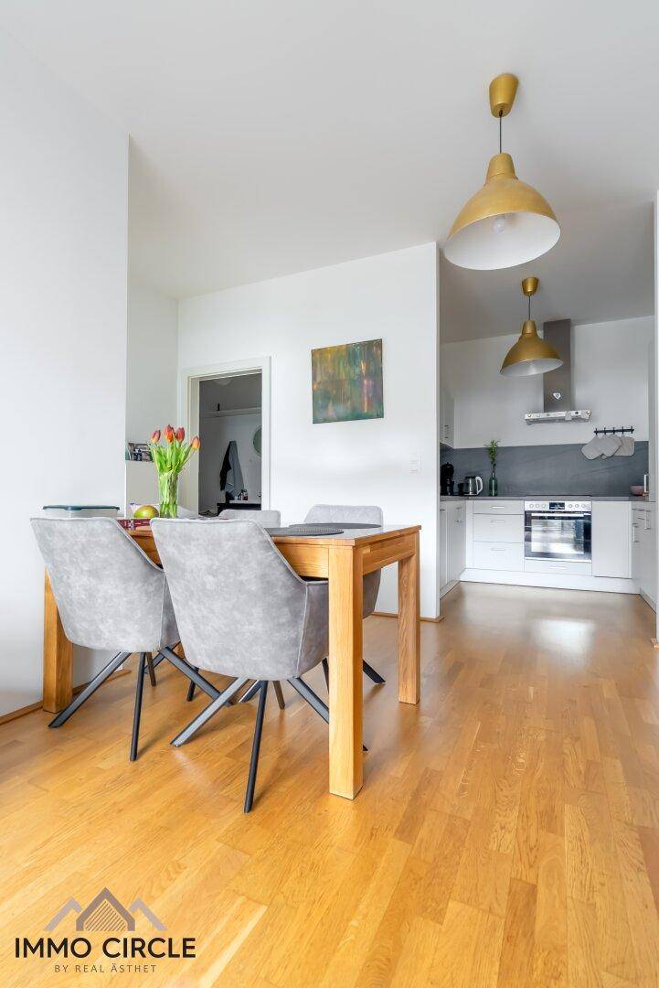 Offener Essbereich mit Holztisch und Blick in die angrenzende moderne Küche.