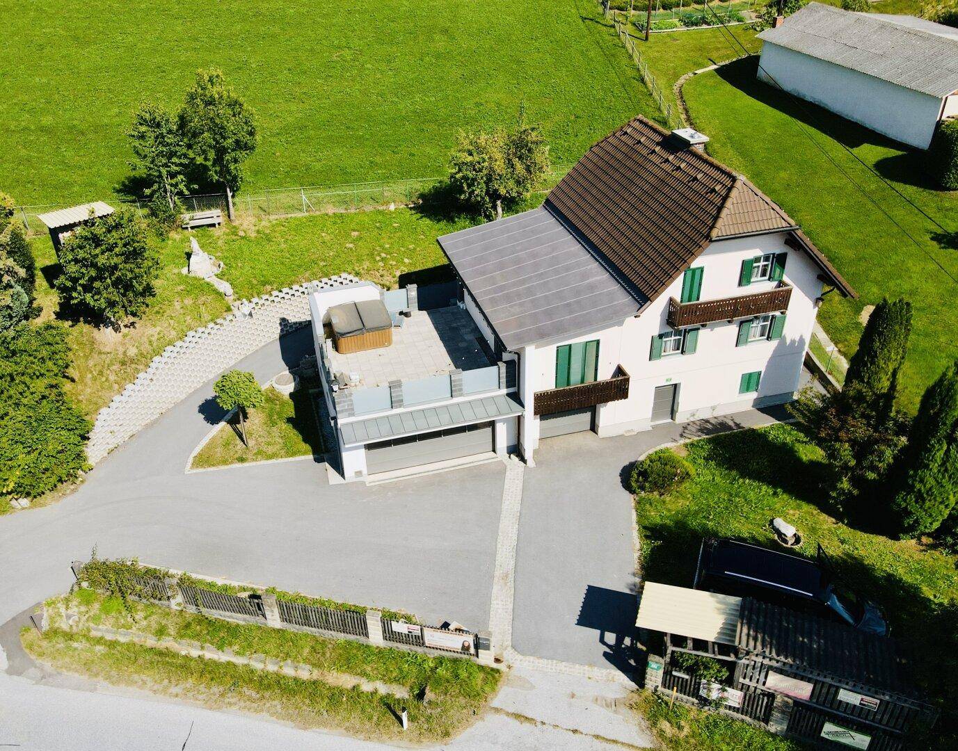 Weitläufige Luftaufnahme des Anwesens mit Photovoltaikanlage und umgebenden grünen Wiesen.