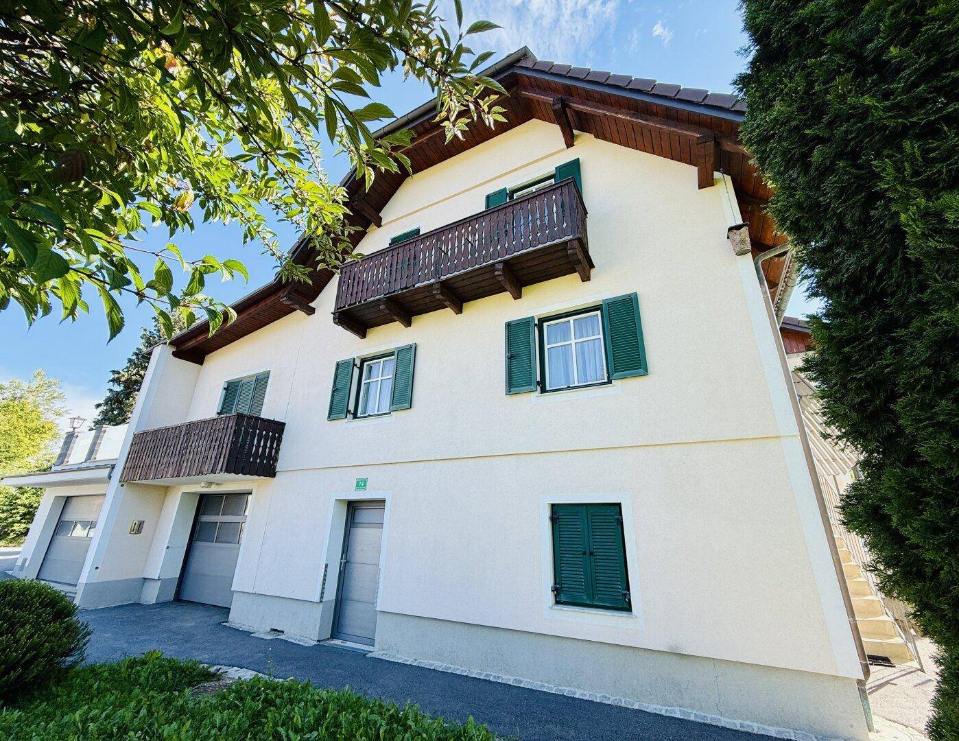 Ansicht des Hauses von unten mit Balkonen, Garagen und traditionellen Holzdetails.