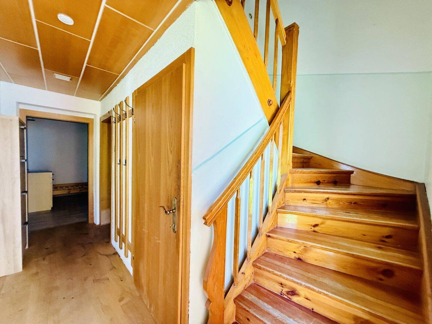 Flur mit Holztreppe und Holzverkleidung an Decke und Wänden.
