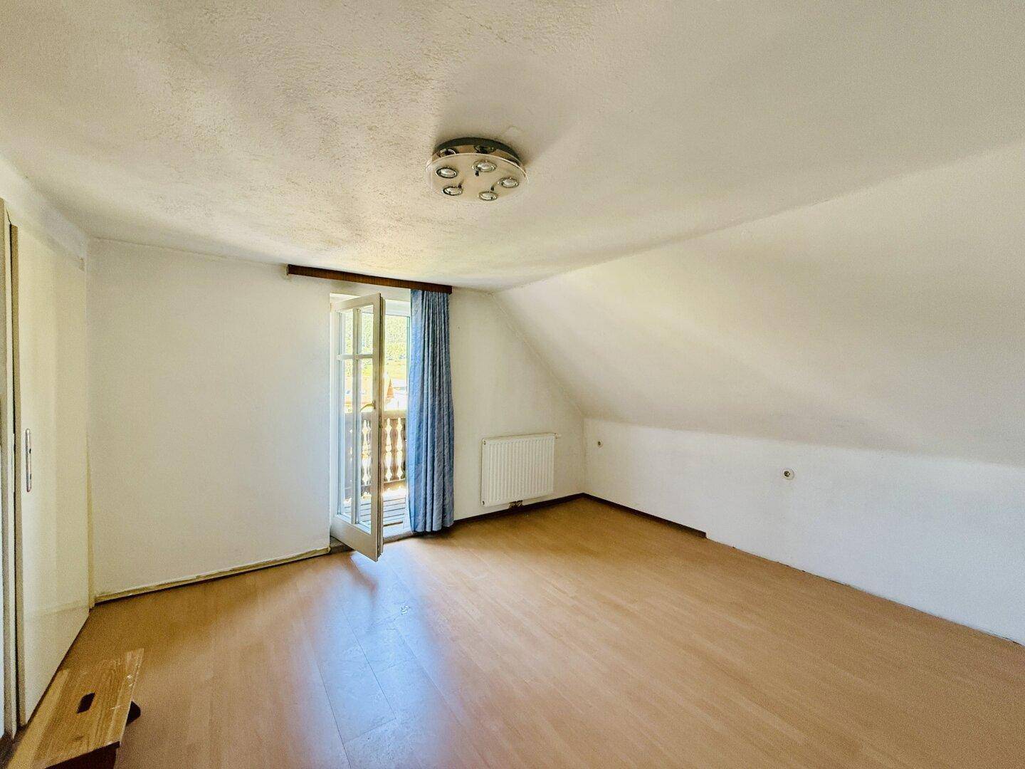 Geräumiges Schlafzimmer mit Zugang zum Balkon und Laminatboden.
