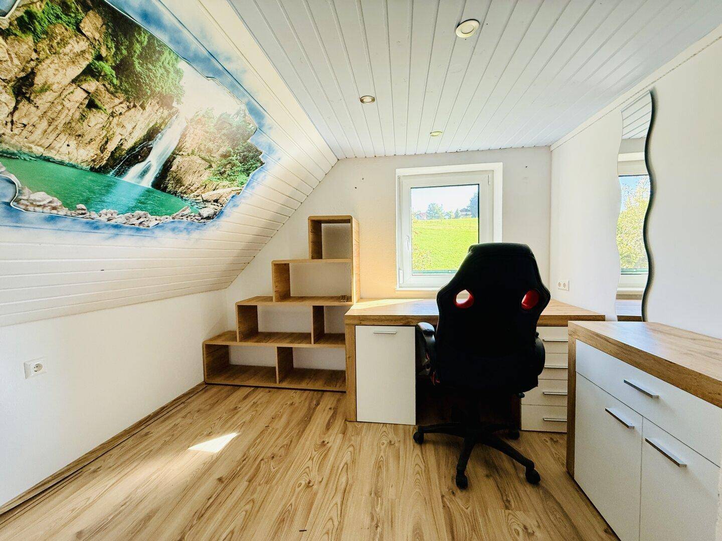 Helles Arbeitszimmer mit Schreibtisch, Regalen und Blick ins Grüne.