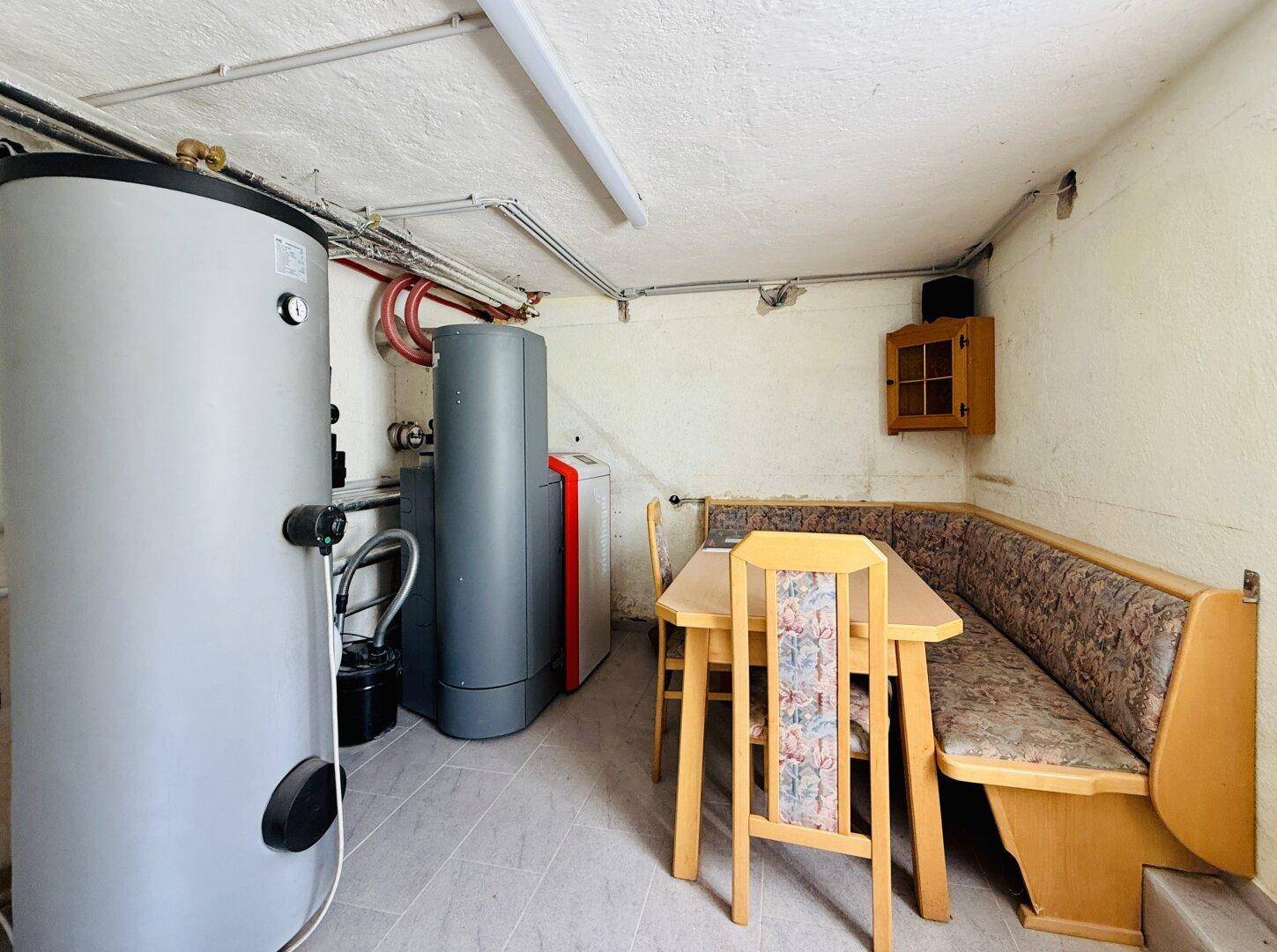 Heizungsraum mit Warmwasserspeicher und kleinem Essbereich.