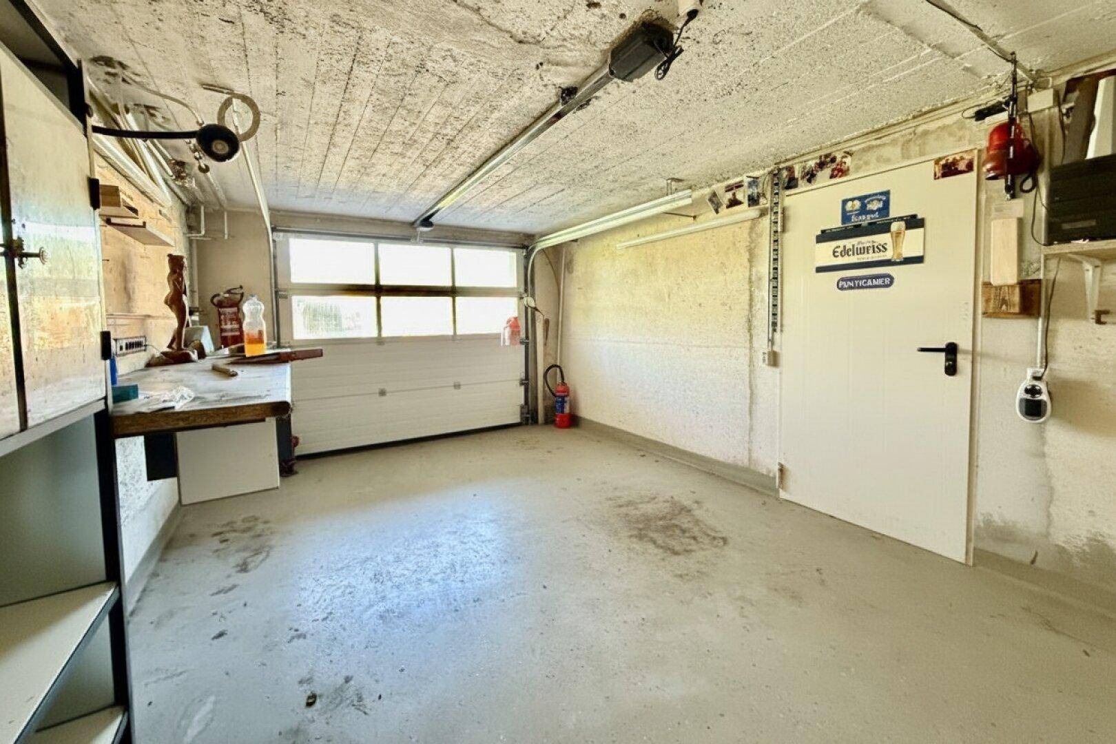 Funktionale Garage mit Betonboden, Rolltor und direktem Zugang zum Gebäude.