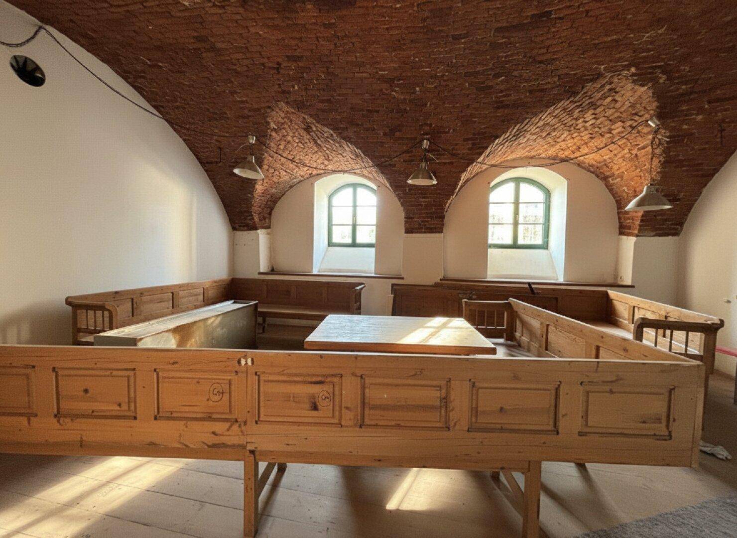 Gastraum mit Holzbänken und Tischen, charakteristischen Ziegelgewölbedecken und Bogenfenstern, die natürliches Licht hereinlassen.