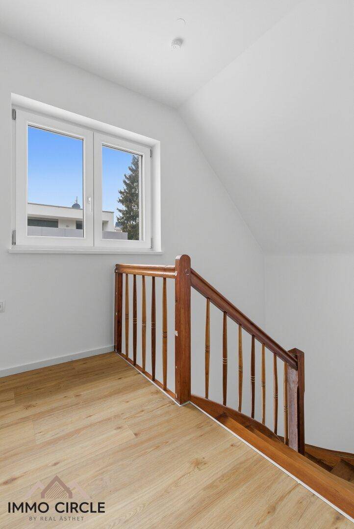 Treppenaufgang mit Holzgeländer und Holzboden, führt zu den oberen Etagen des Hauses.