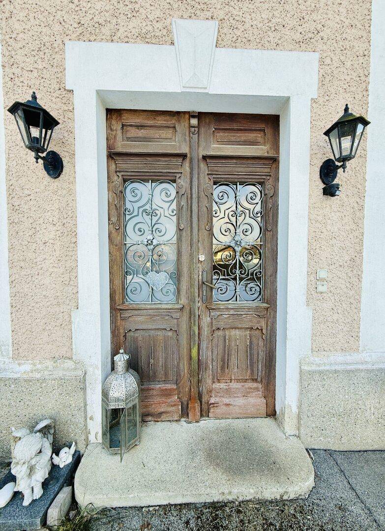 Detailansicht einer alten Holztür mit kunstvollen Gittern und zwei traditionellen Wandlaternen.