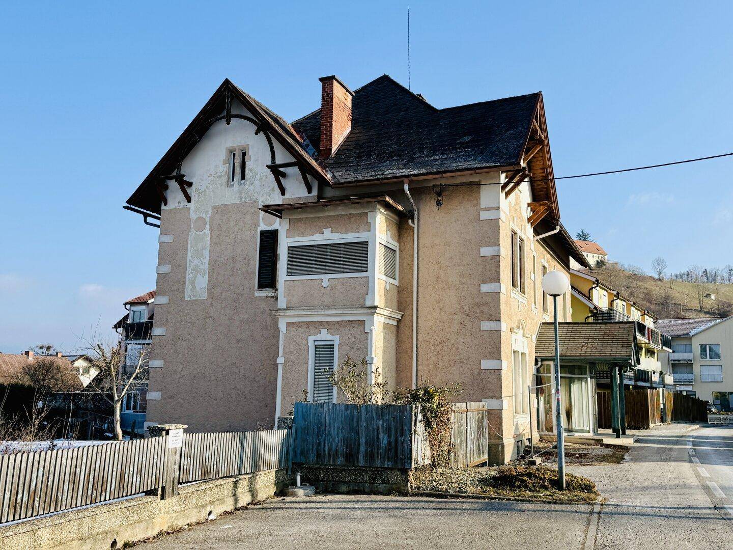 Seitenansicht des historischen Gebäudes mit traditioneller Architektur und einem Satteldach unter blauem Himmel.