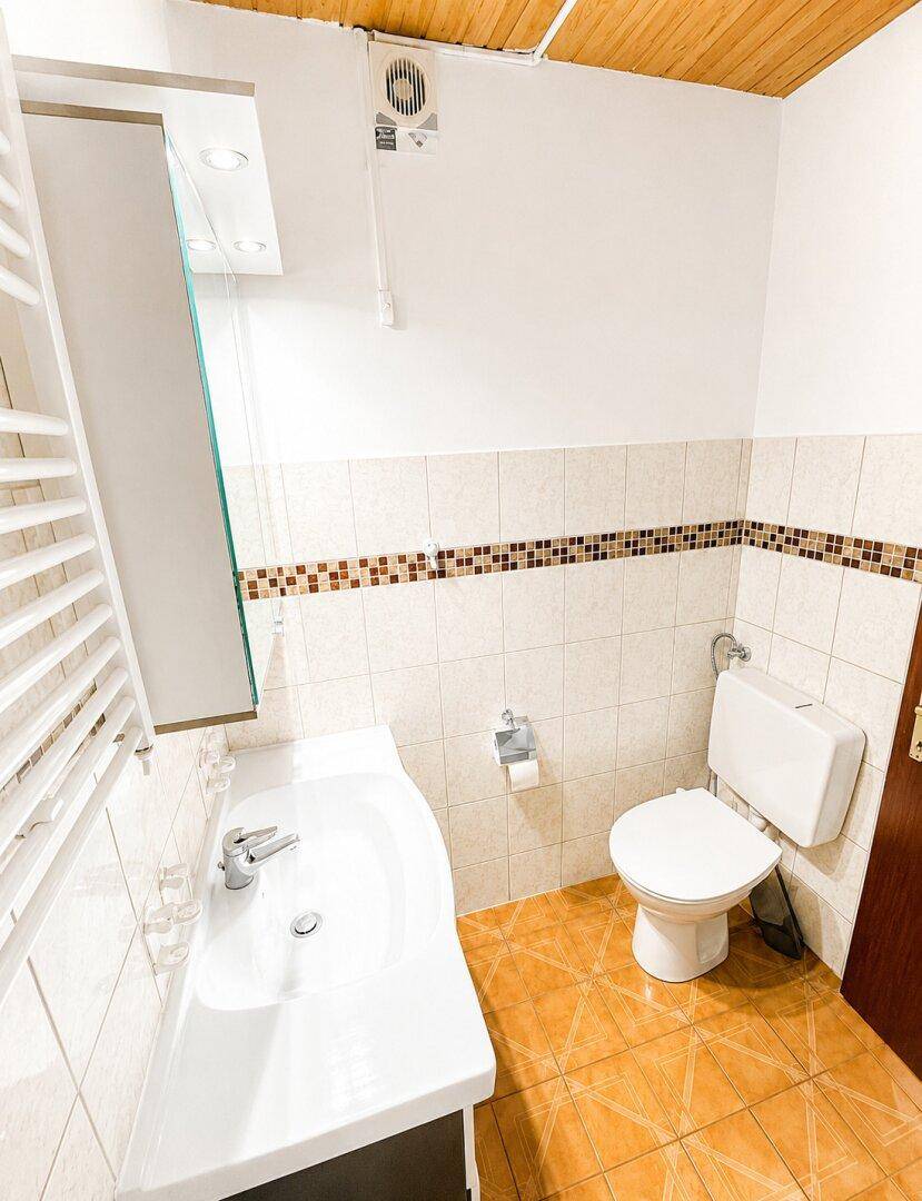 Badezimmer mit Waschbecken, Toilette, Spiegelschrank und gefliesten Wänden und Böden.
