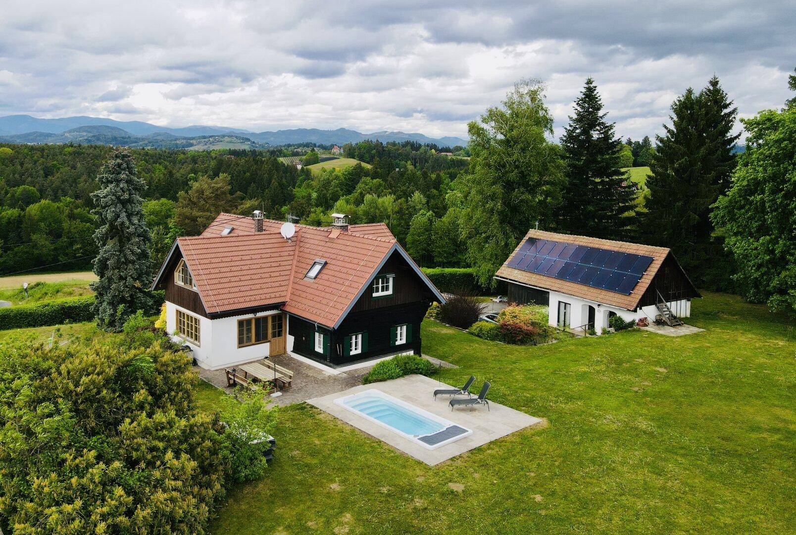 Panoramablick auf ein charmantes Landhaus mit Pool und separatem Gebäude mit Solaranlage.