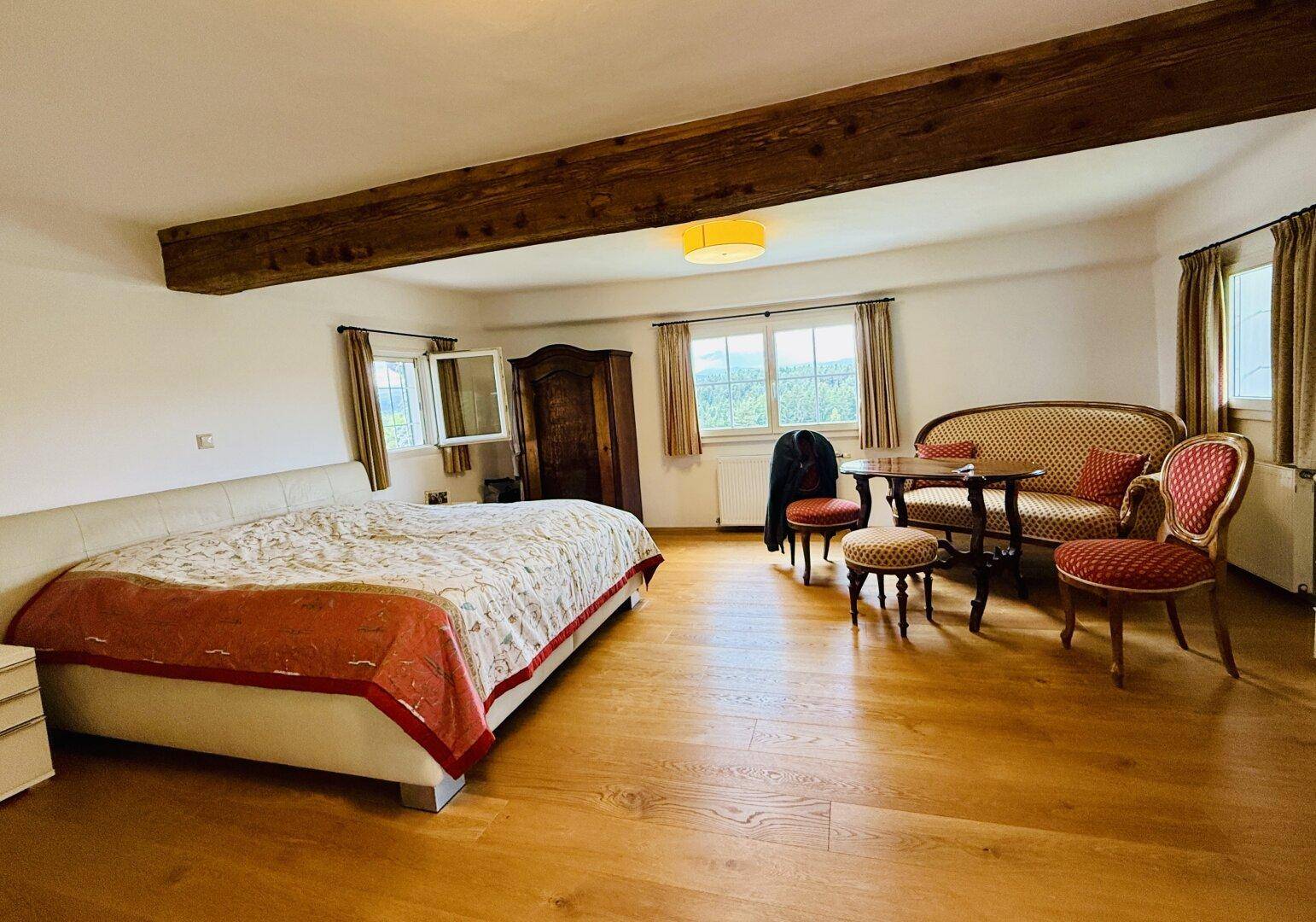 Geräumiges Schlafzimmer mit Doppelbett, antiken Möbeln, Holzbalken und Holzboden.