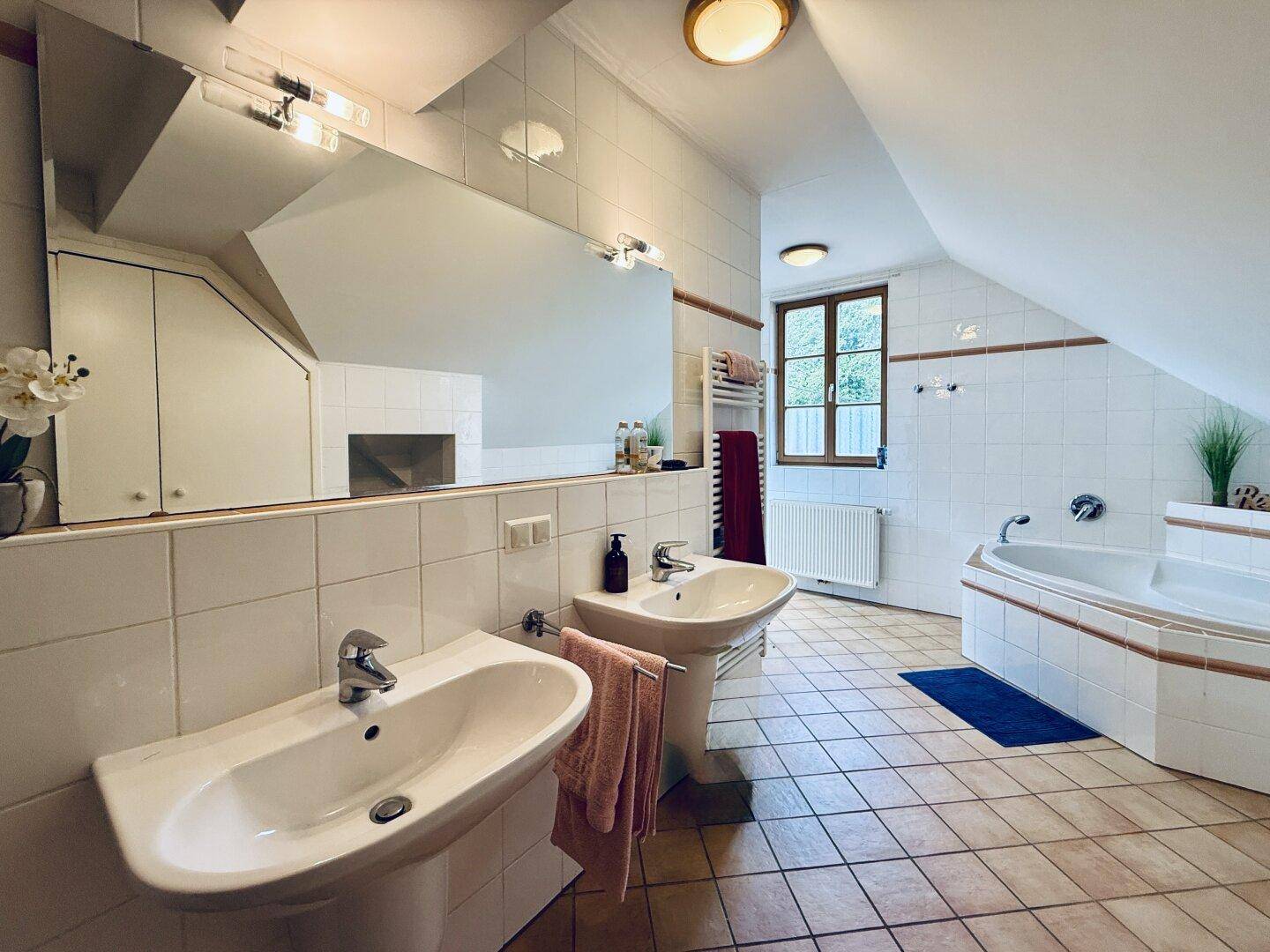 Geräumiges Badezimmer im Dachgeschoss mit Doppelwaschbecken, Eckbadewanne und Fliesenboden.