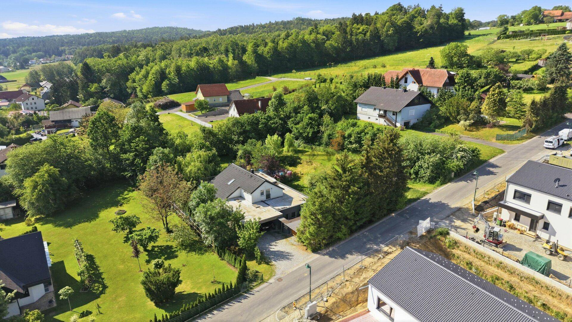 Weitläufige Luftaufnahme der Wohngegend mit viel Grün und dem Haus in ländlicher Umgebung.