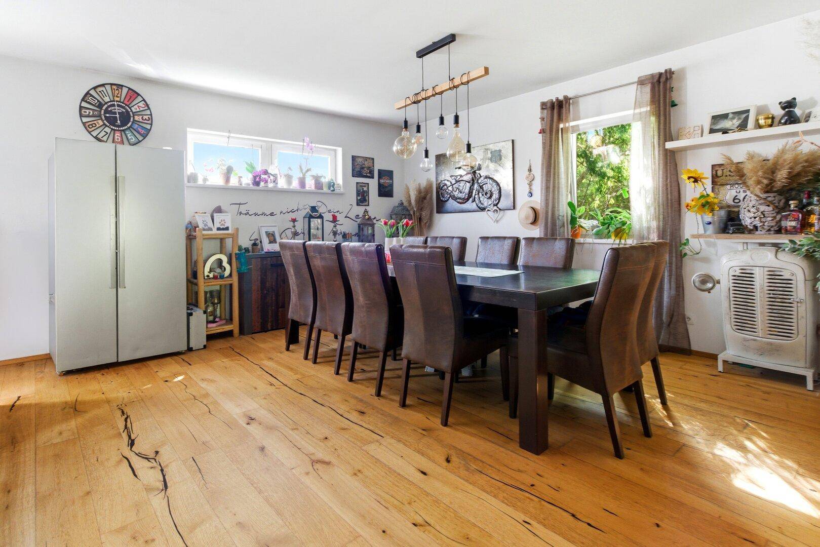 Geräumiger Essbereich mit großem Holztisch, Ledersesseln und rustikalem Holzboden.