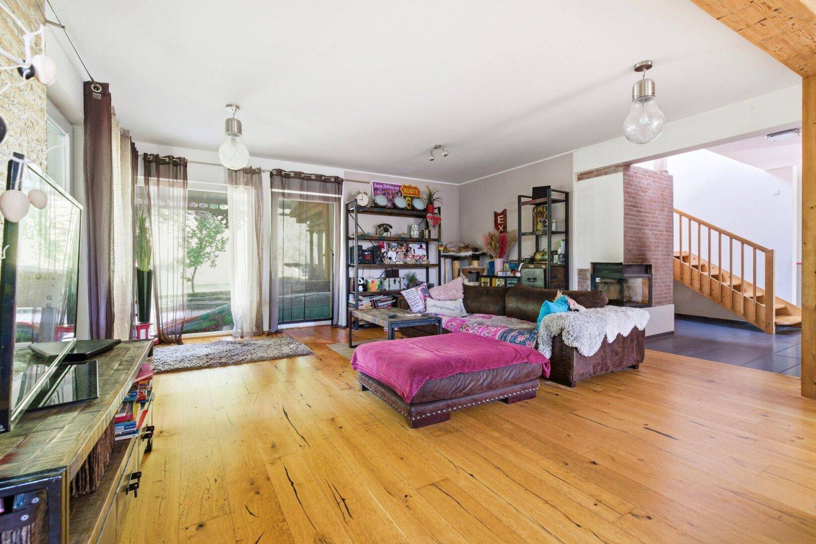 Gemütliches Wohnzimmer mit Holzboden, bequemen Sofas und Zugang zur Terrasse.