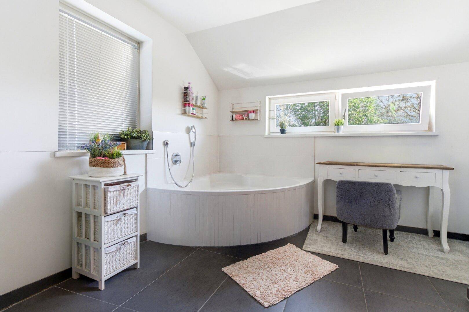 Helles Badezimmer im Dachgeschoss mit runder Badewanne und Fenstern.