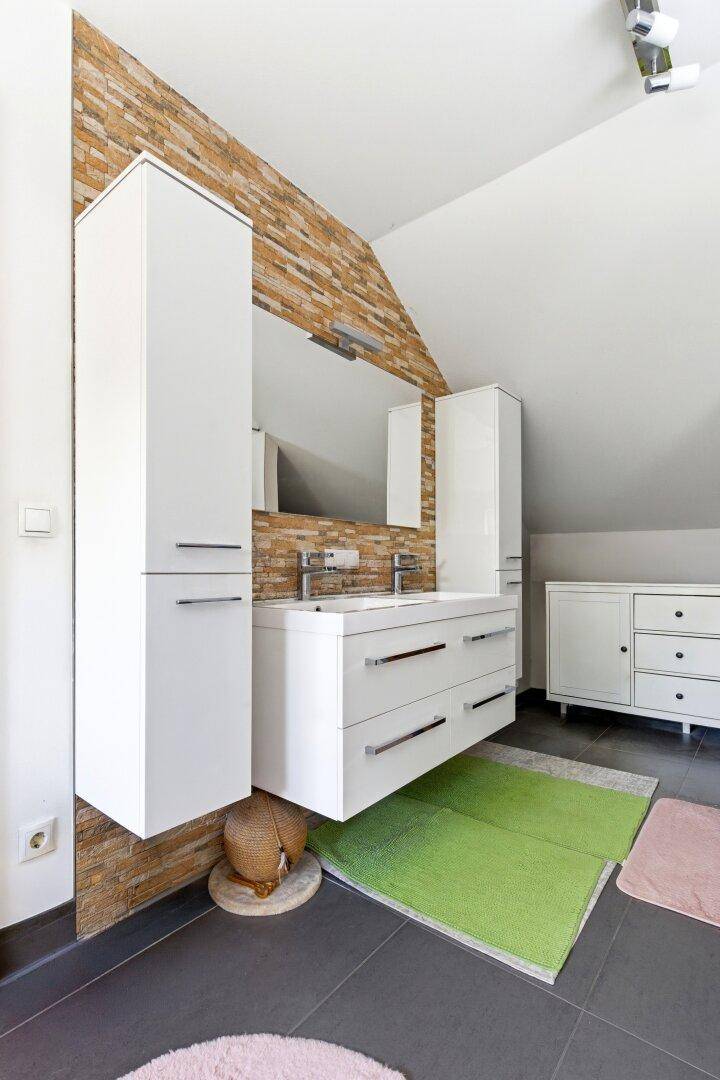 Modernes Badezimmer im Dachgeschoss mit Doppelwaschbecken und Steinwand.