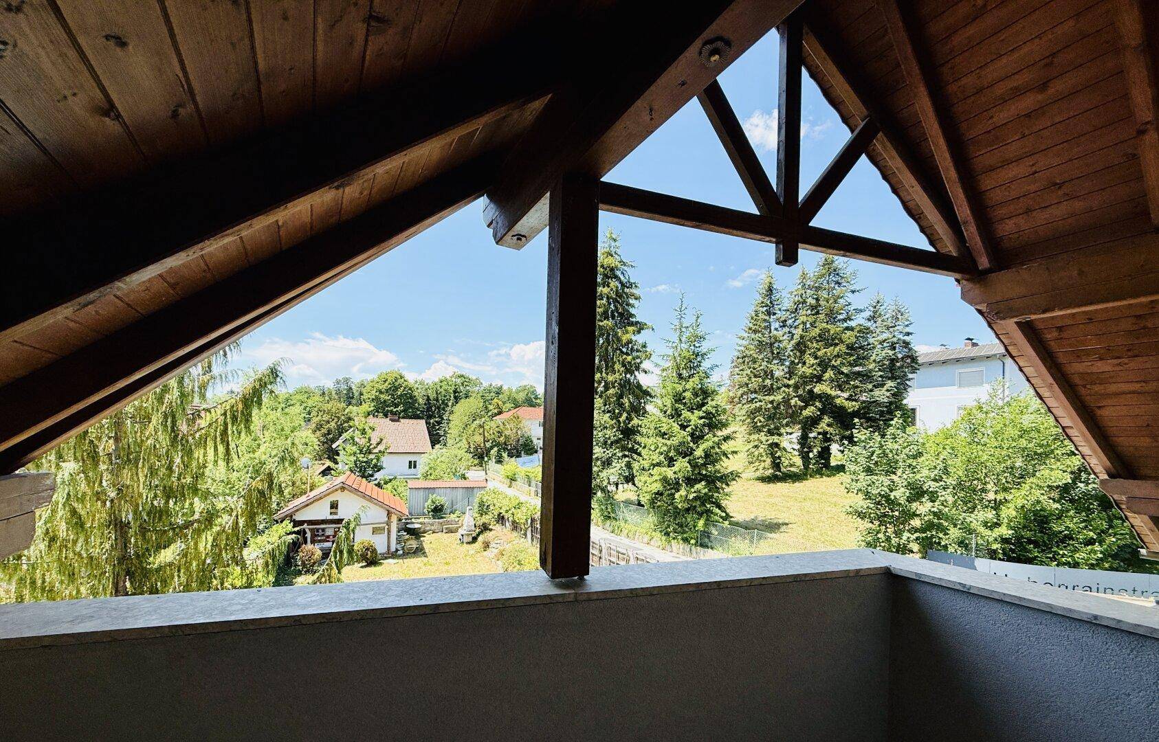 Balkon mit rustikaler Holzkonstruktion und weitem Blick über die Landschaft.