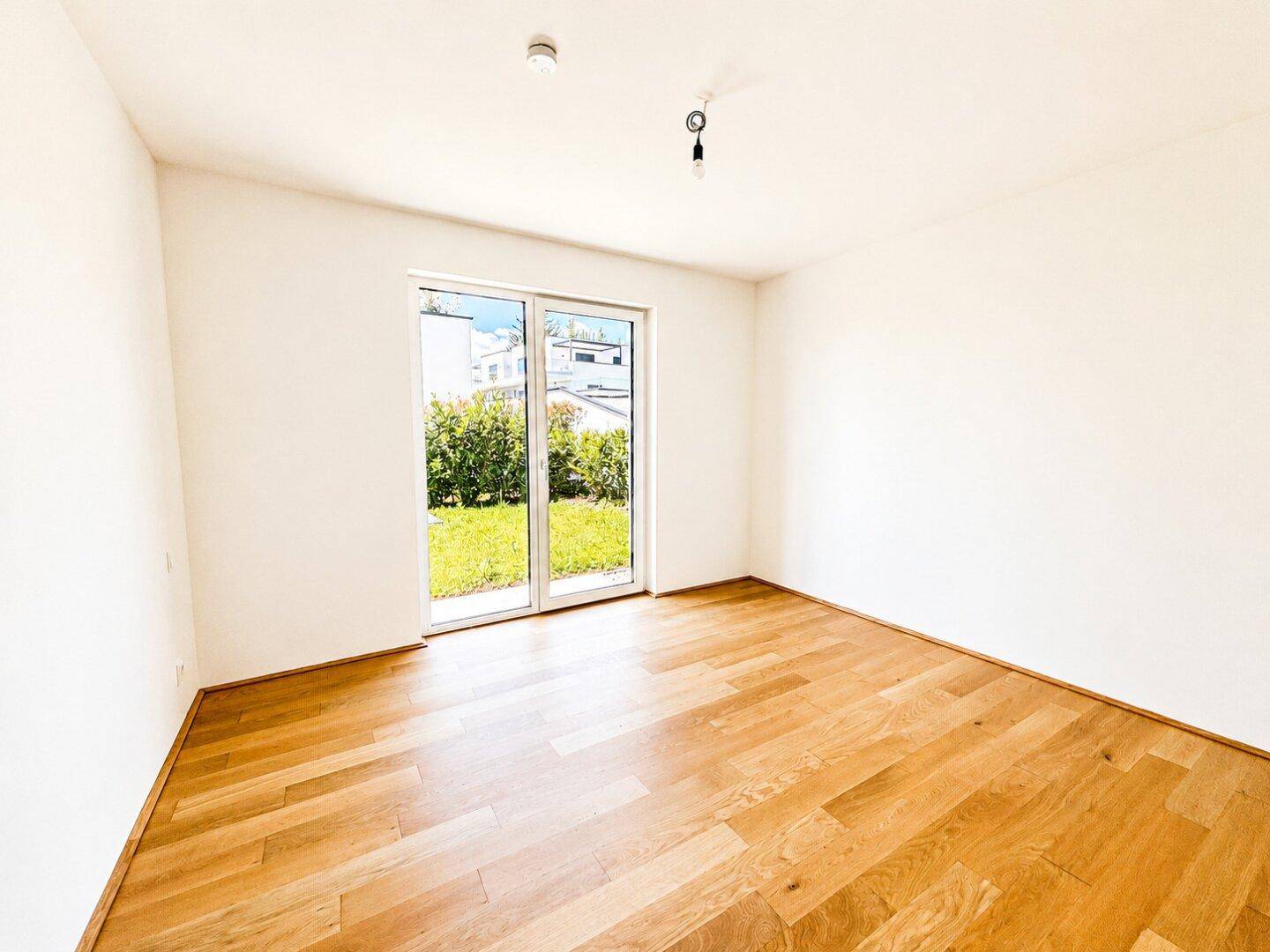 Helles Schlafzimmer mit Holzboden und direktem Zugang zu einem privaten Außenbereich.