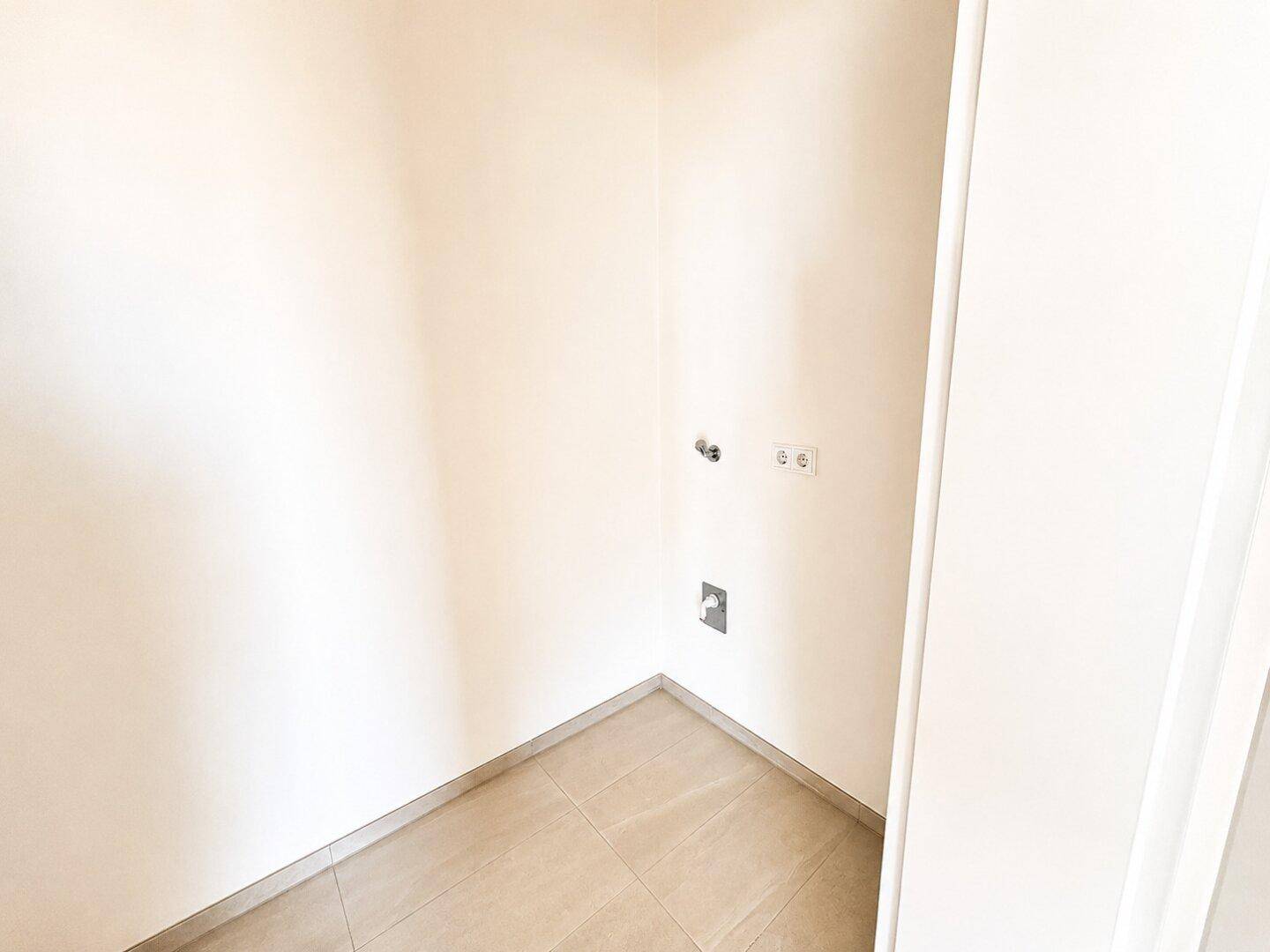 Praktischer Hauswirtschaftsraum mit Fliesenboden und Anschlüssen für Waschmaschine.