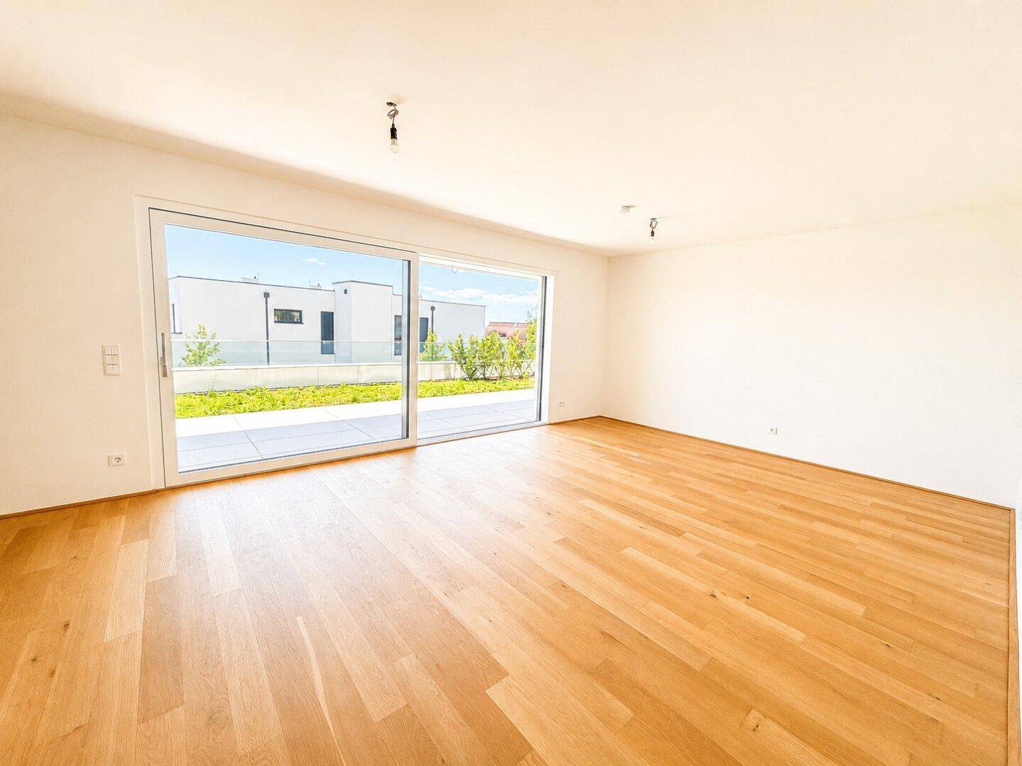 Großzügiges Wohnzimmer mit Eichenparkett und raumhohen Schiebetüren für viel Licht.