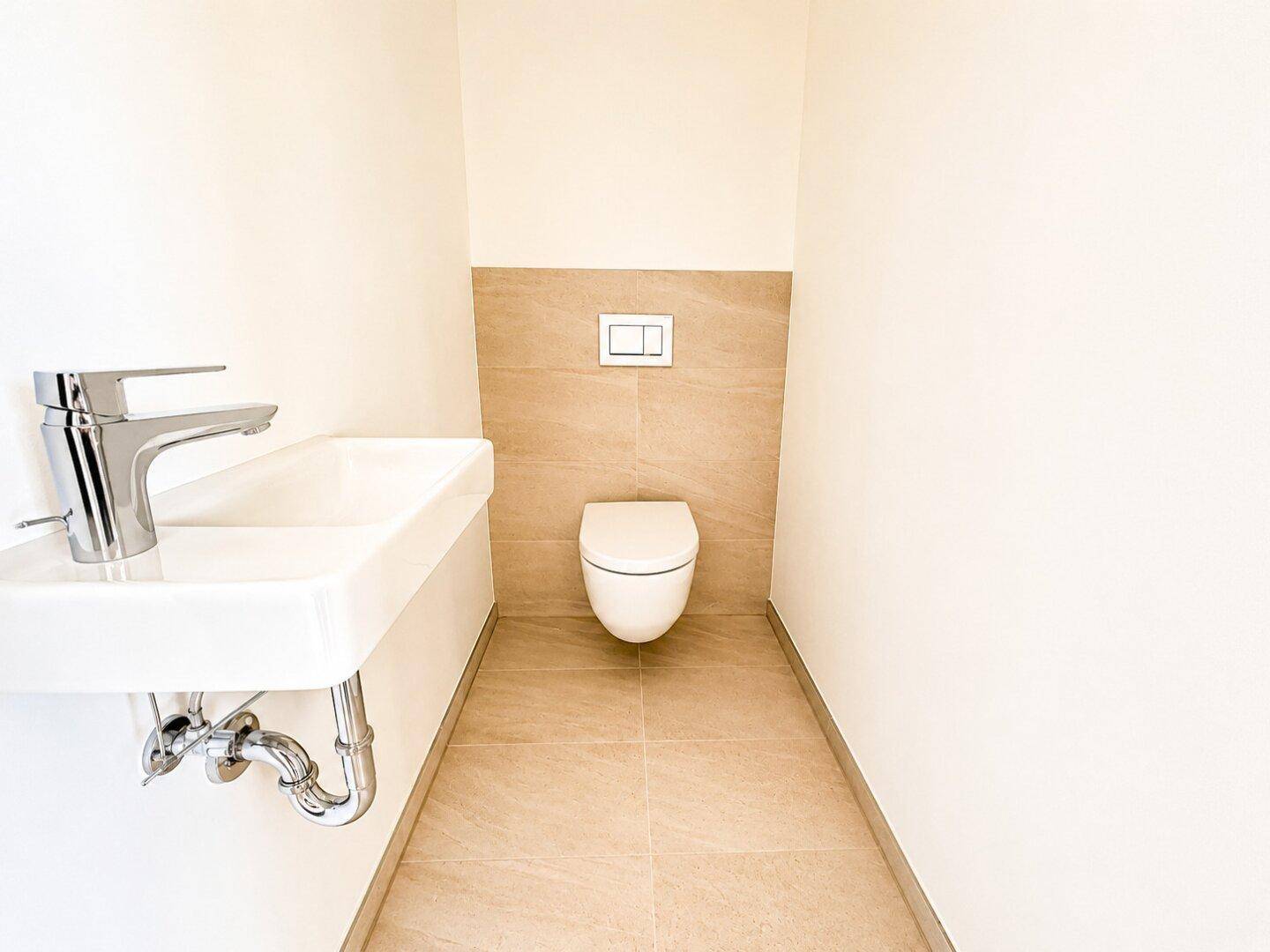 Modernes Gäste-WC mit wandhängender Toilette und kleinem Waschbecken.