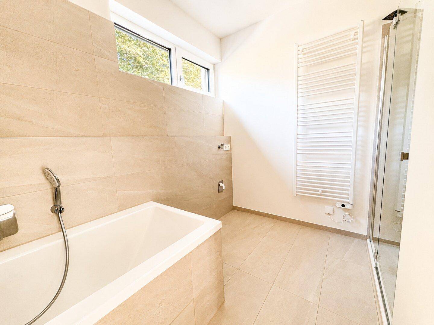 Geräumiges Badezimmer mit Badewanne, Duschbereich und einem Fenster für Tageslicht.