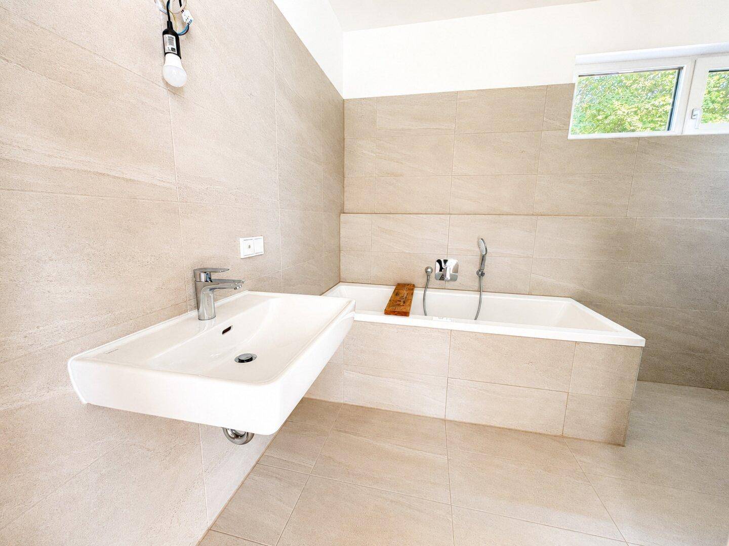Helles Badezimmer mit modernem Waschbecken und integrierter Badewanne.