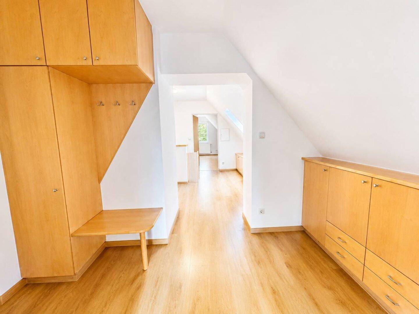 Langer Flur im Dachgeschoss mit praktischen Einbauschränken und hellem Holzboden.