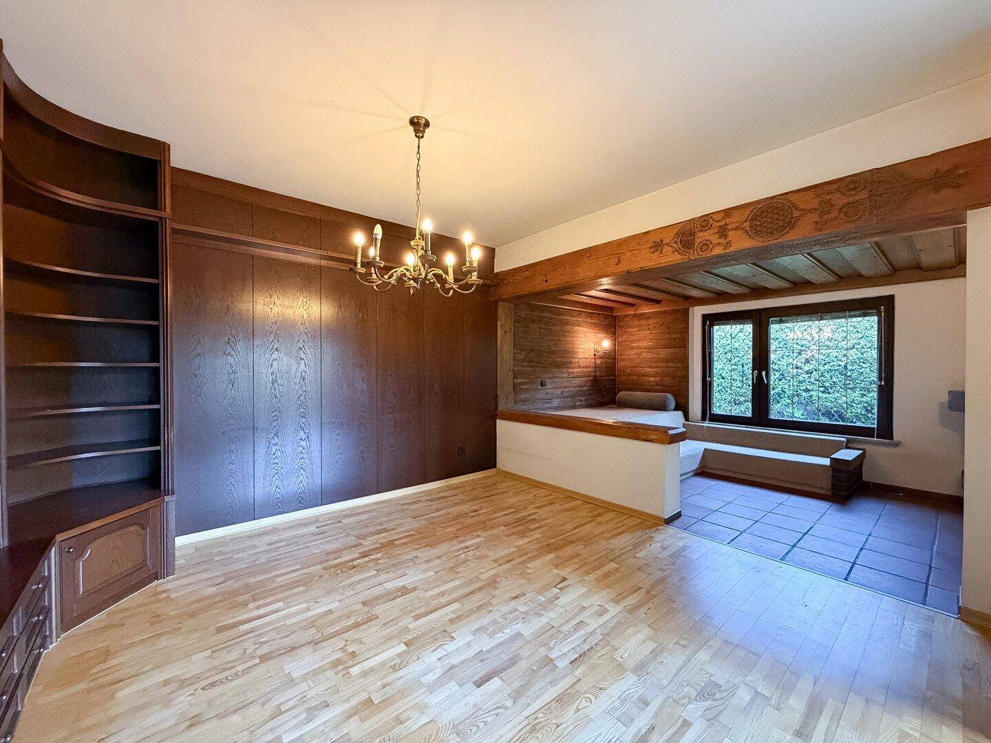 Geräumiges Wohnzimmer mit Holzboden, Wandvertäfelung und rustikalen Holzbalken.