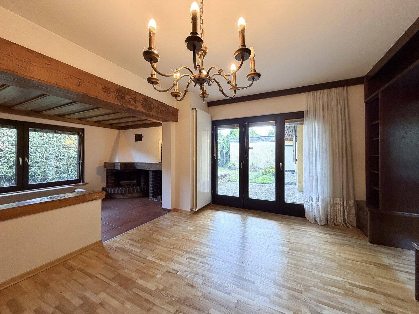 Helles Wohnzimmer mit Holzboden, Kamin und direktem Zugang zur Terrasse.