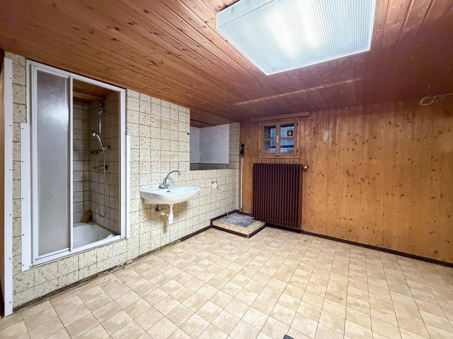 Rustikales Badezimmer mit Holzvertäfelung, Duschkabine und Fliesenboden.