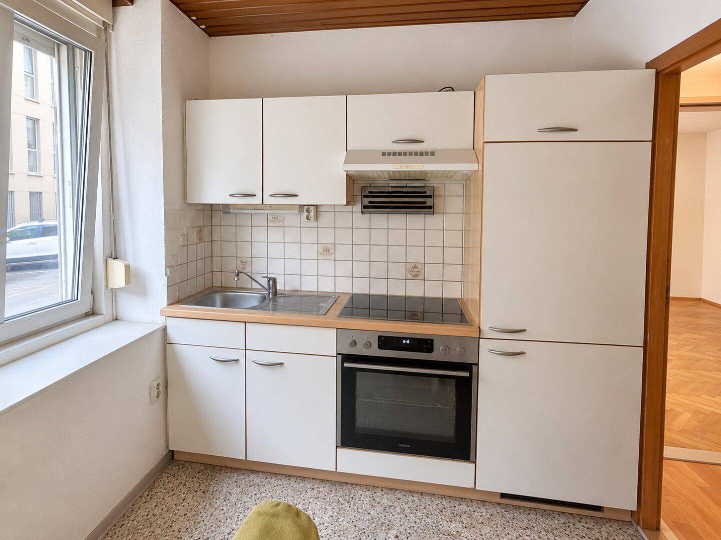 Nahaufnahme der Einbauküche mit weißen Fronten, Kochfeld und Backofen, ideal für den täglichen Gebrauch.