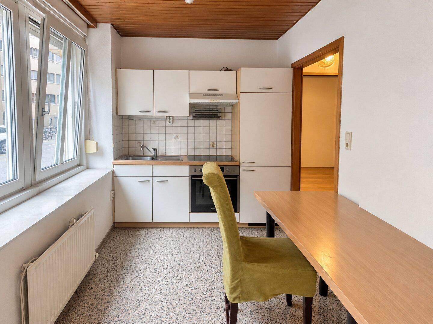 Funktionale Küche mit weißen Schränken, Kochfeld und Essbereich, ausgestattet mit einem Tisch und Stuhl.