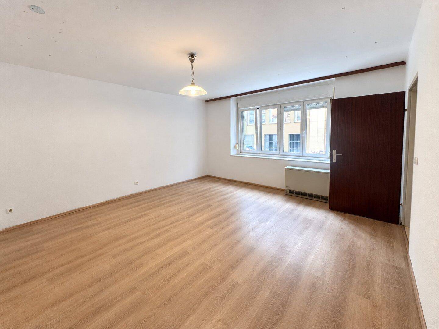 Helles Zimmer mit Laminatboden und Fenster, das viel Tageslicht hereinlässt, vielseitig nutzbar.