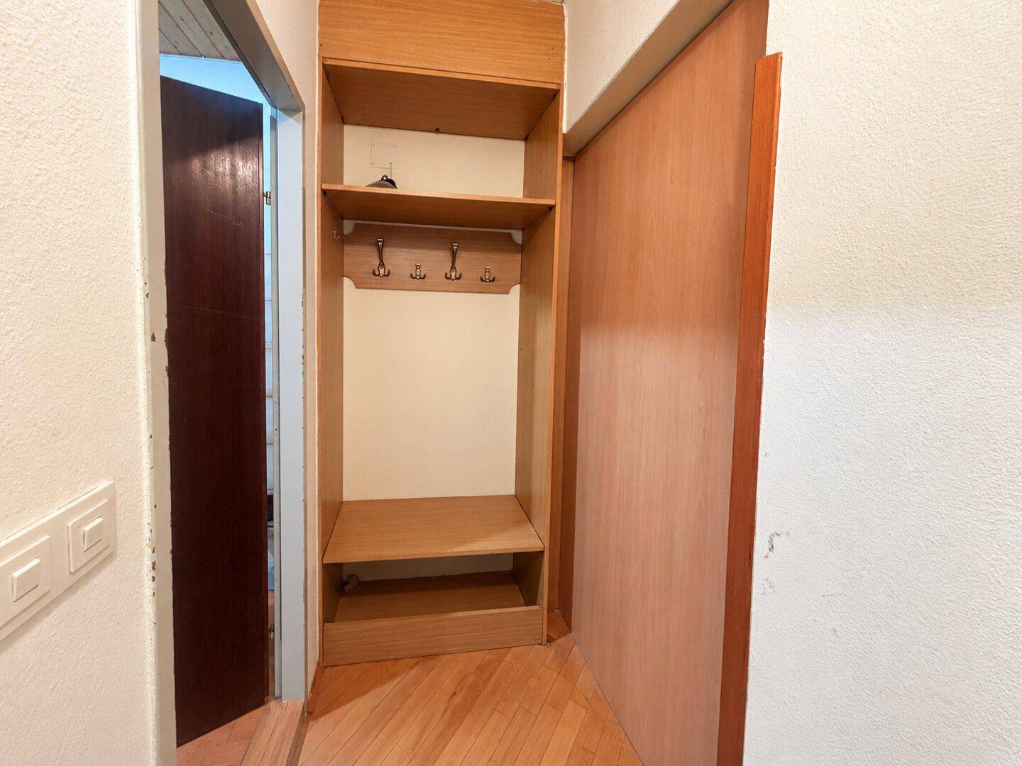Eingangsbereich mit integrierter Garderobe und Holzregalen, bietet praktischen Stauraum.