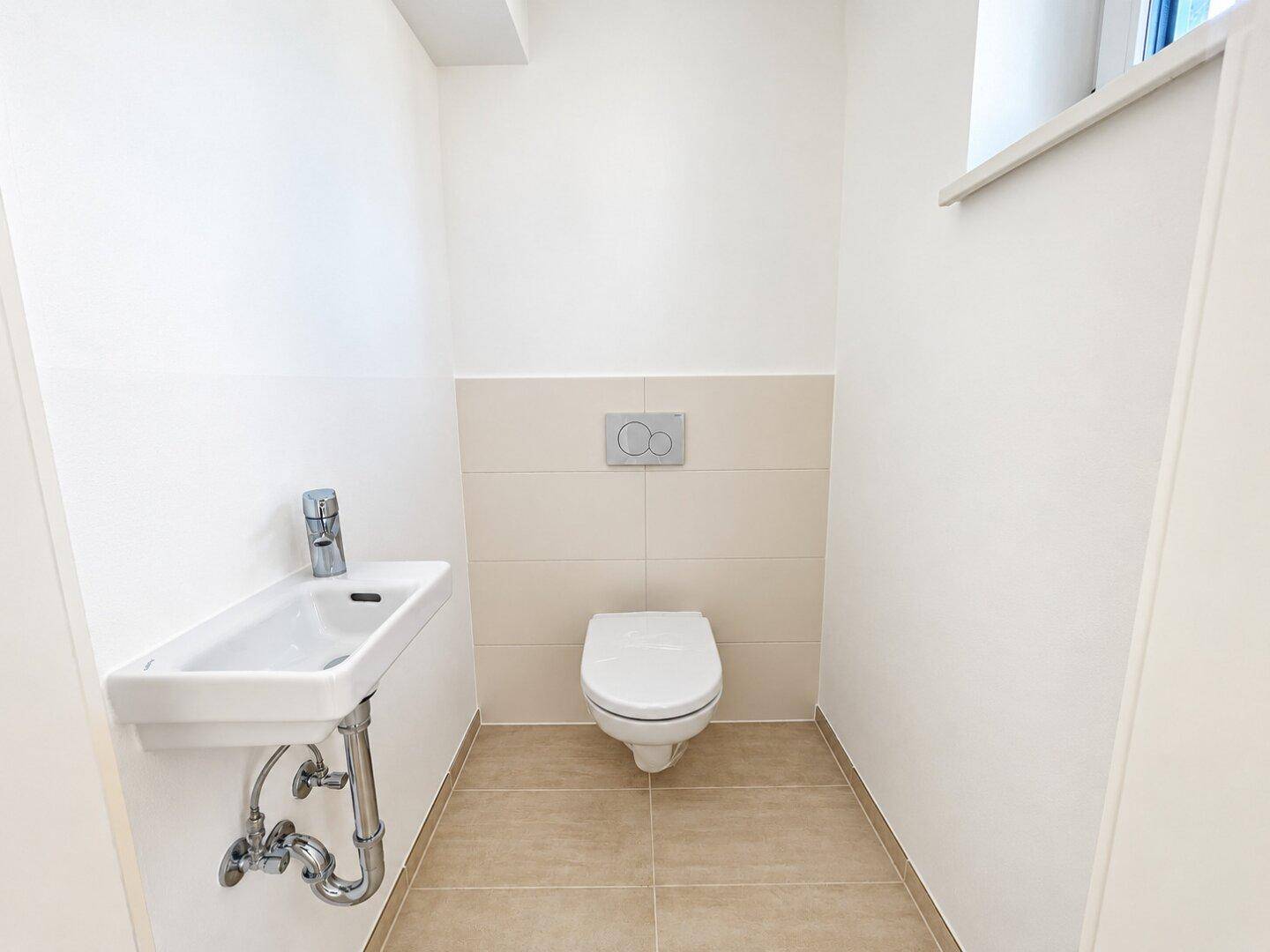 Modernes Gäste-WC mit wandhängender Toilette und kleinem Waschbecken.