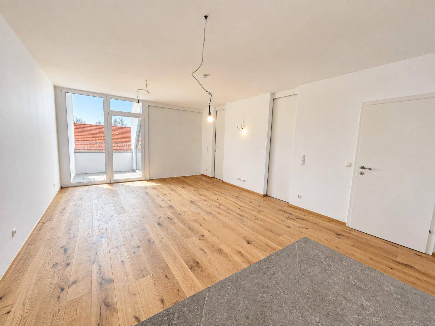 Geräumiger, heller Wohnbereich mit Holzboden und offener Gestaltung, bereit für die Einrichtung.