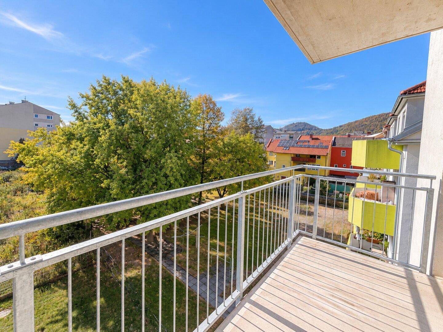 Geräumiger Balkon mit Holzboden und weitem Blick ins Grüne und auf die Nachbarschaft.