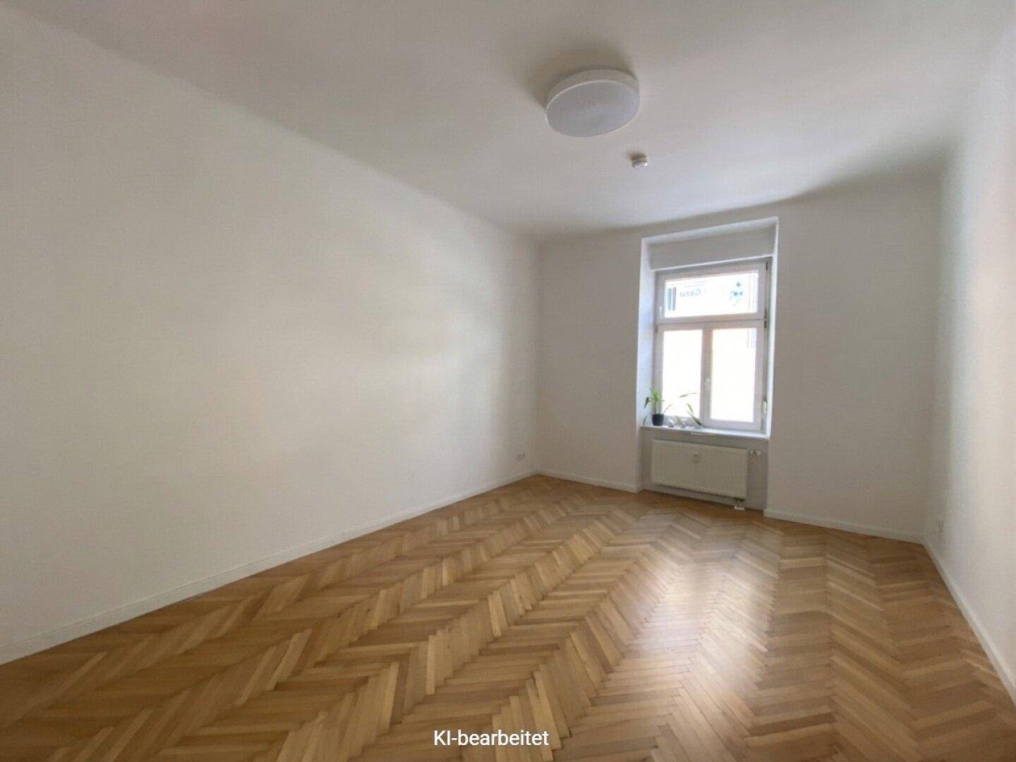 Geräumiger, heller Raum mit klassischem Fischgrätparkett und einem großen Fenster.