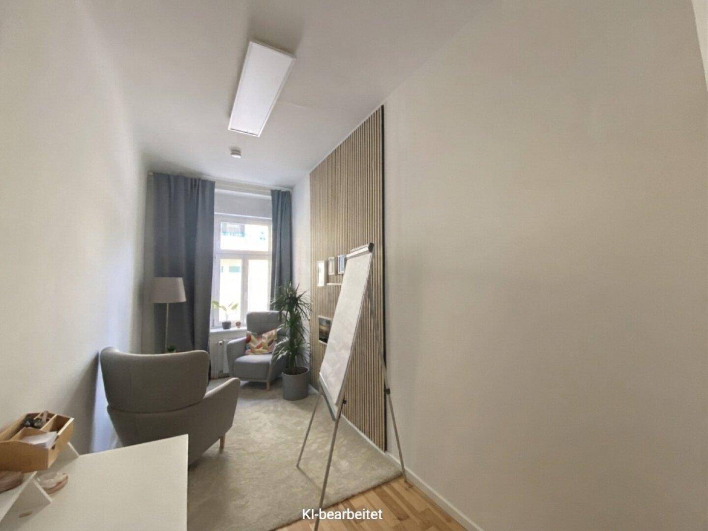 Gemütlicher Büroraum mit Teppichboden, einem Sessel, Holzlamellenwand und Fenster mit dunklen Vorhängen.