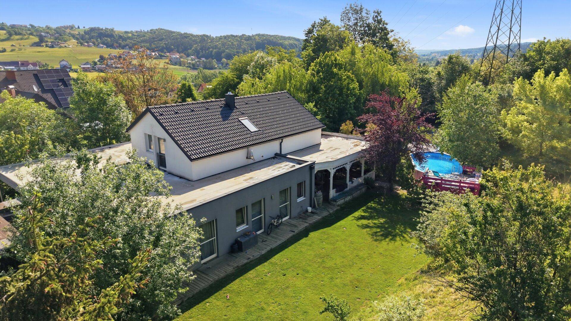 Luftaufnahme des Hauses mit Garten, Pool und der umliegenden grünen Landschaft.