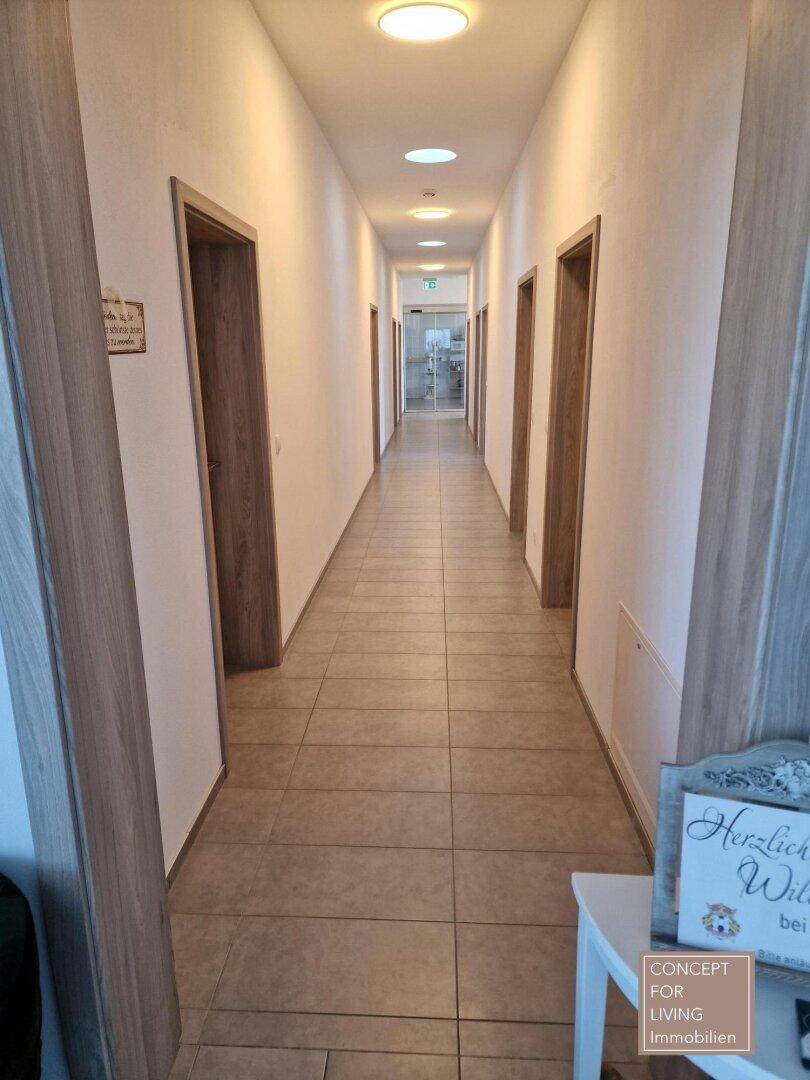 Langer, heller Flur mit Holztüren und Einbauleuchten in der Decke, der zu mehreren Räumen führt.