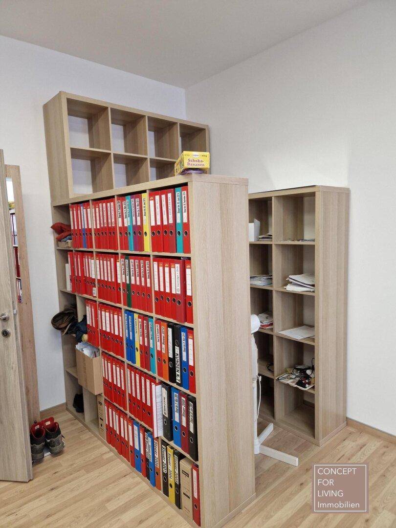 Büro-Lagerbereich mit vielen Aktenordnern in Regalen und Holzboden.