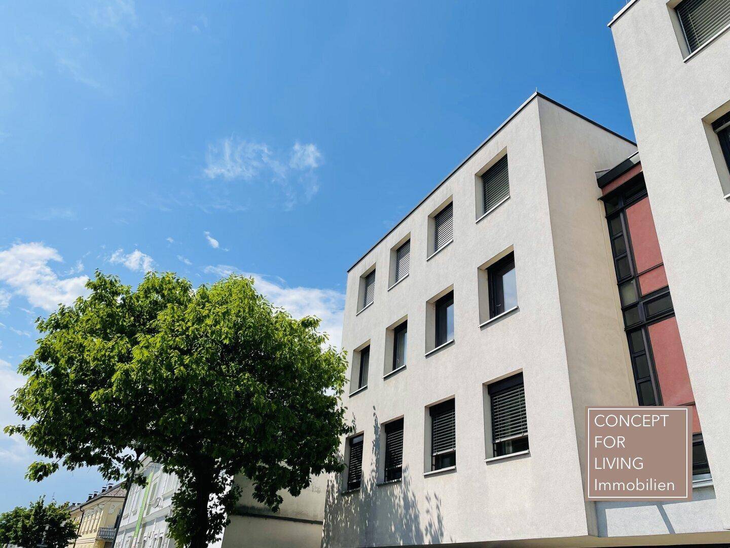 Moderne Gebäudefassade mit vielen Fenstern und Rollläden unter blauem Himmel.