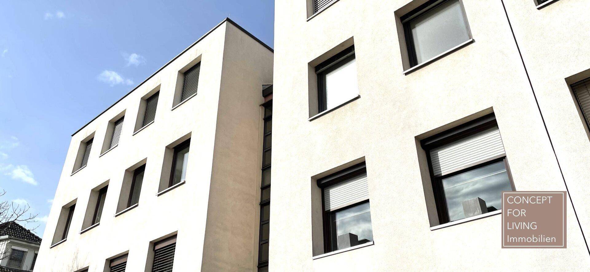 Nahaufnahme der modernen Gebäudefassade mit Fenstern und geschlossenen Rollläden.