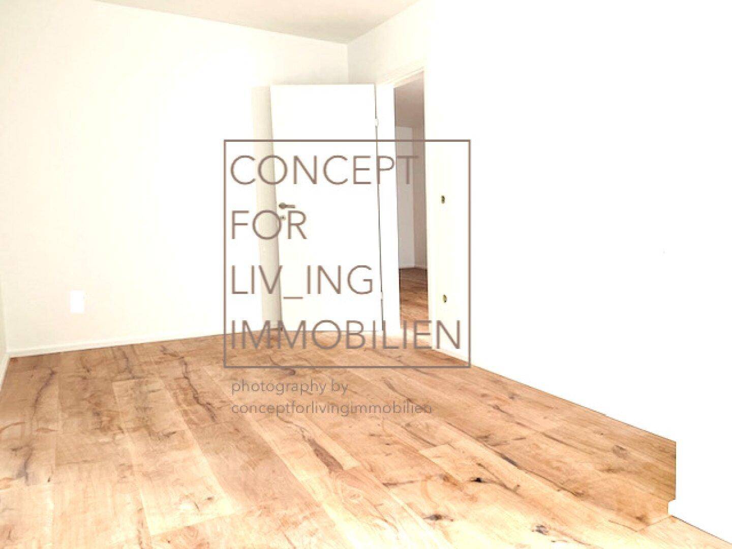 Leerer Raum mit Holzboden und weiß gestrichenen Wänden, bereit zum Einzug.
