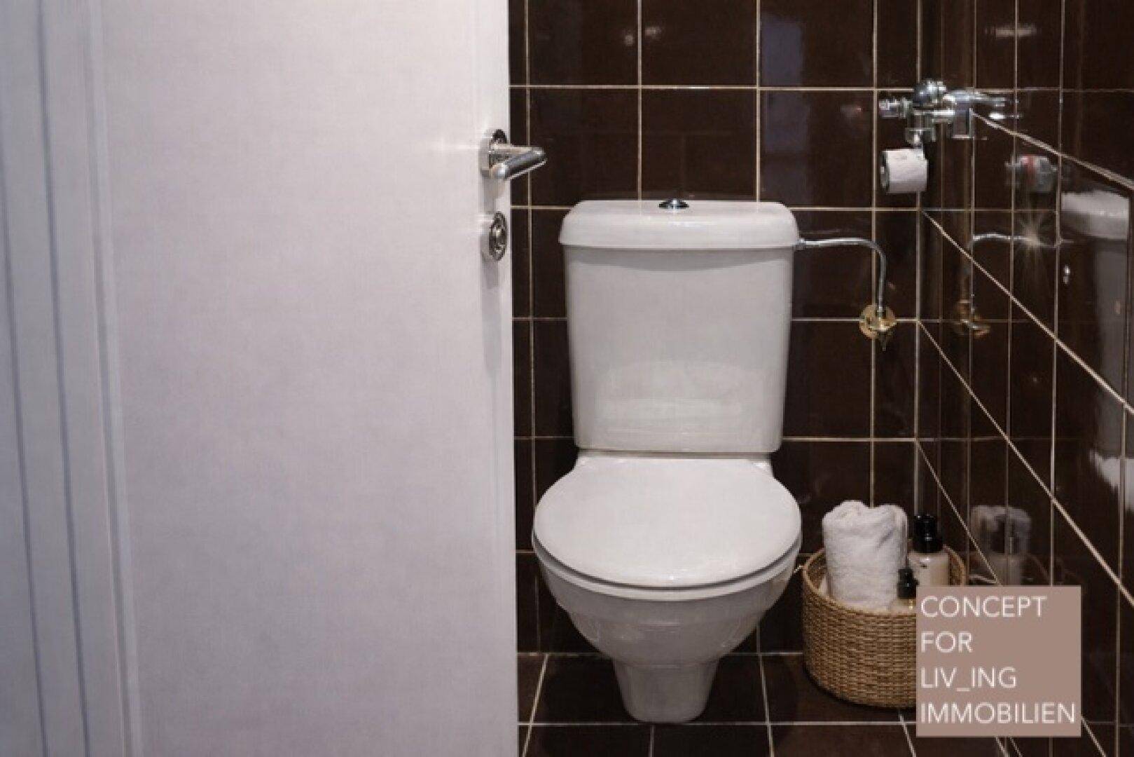 Separate Toilette mit braunen Fliesen und weißer Keramik, sauber und funktional.